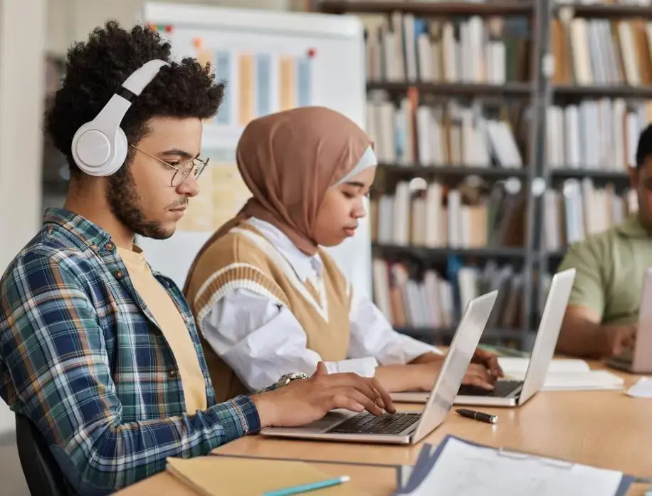 A group of people working with laptops on a library