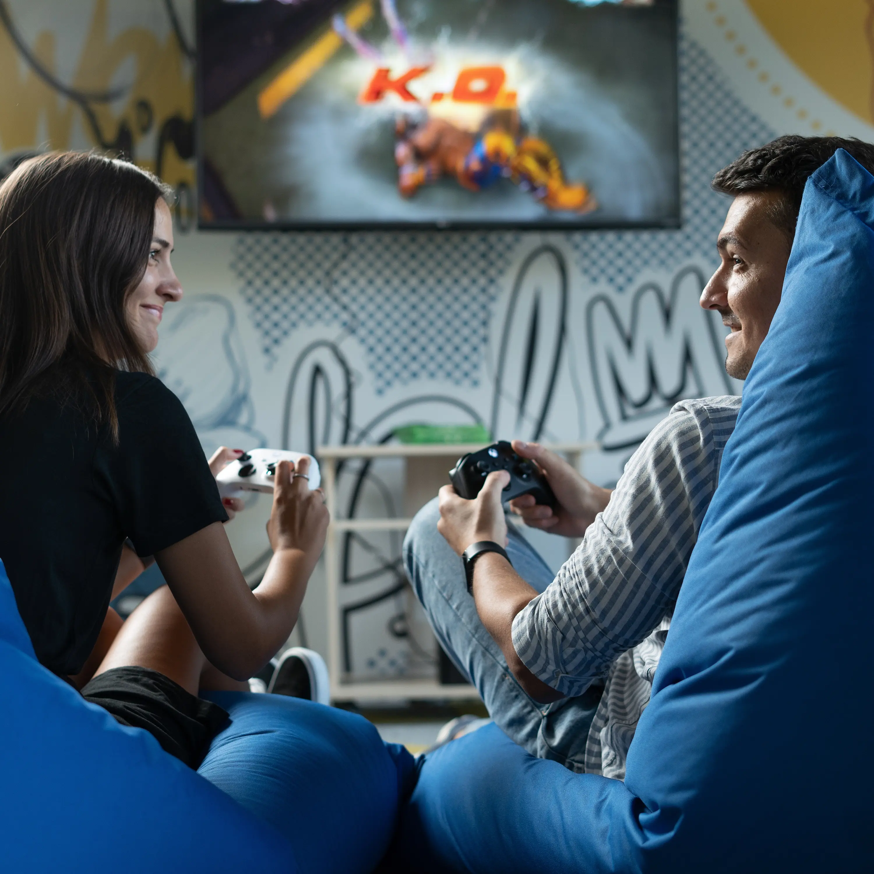 Two friends enjoying video games on comfy bean bags, promoting wellbeing through leisure activities.