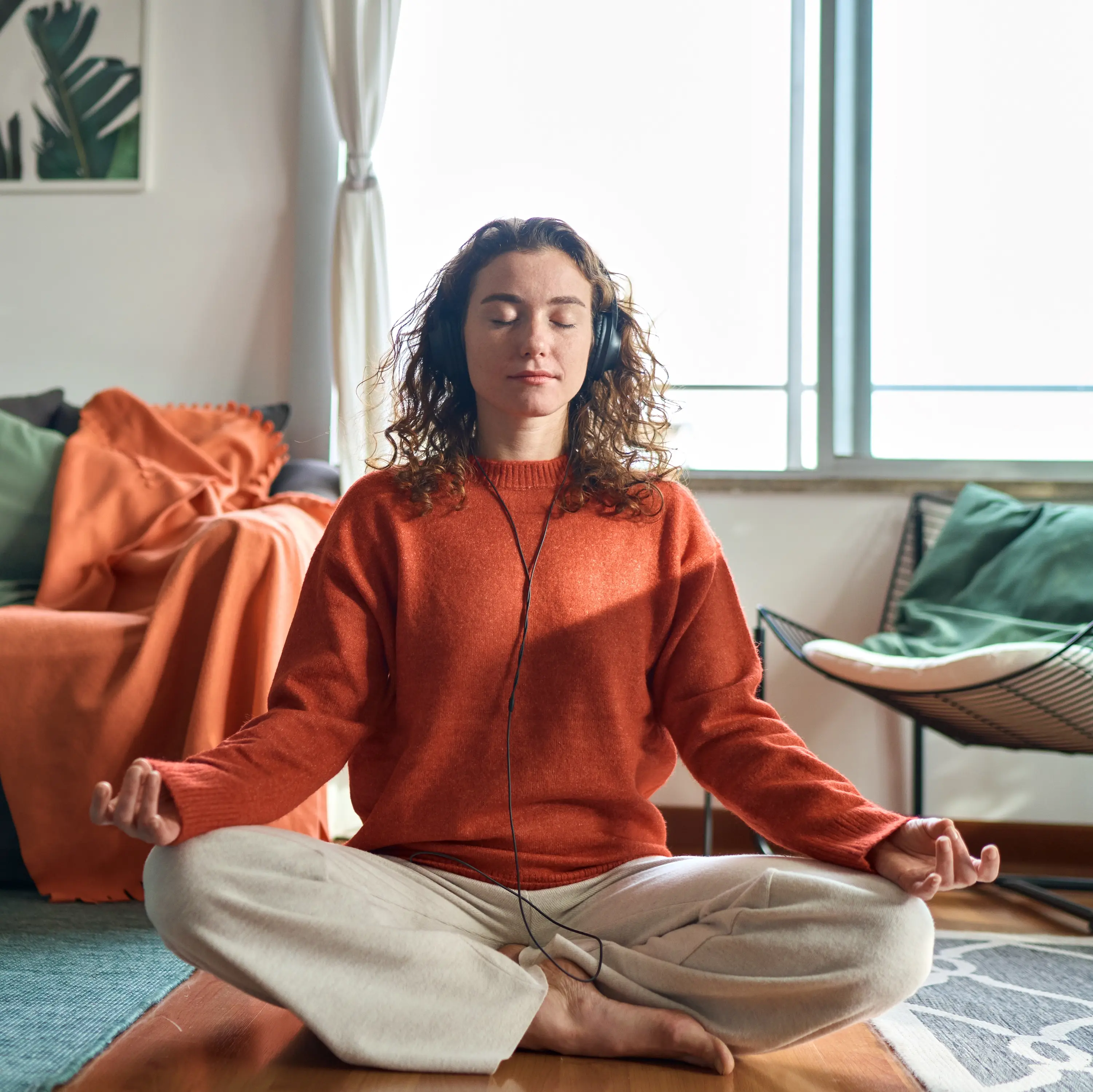 A woman meditating in the living room, focusing on her wellbeing.