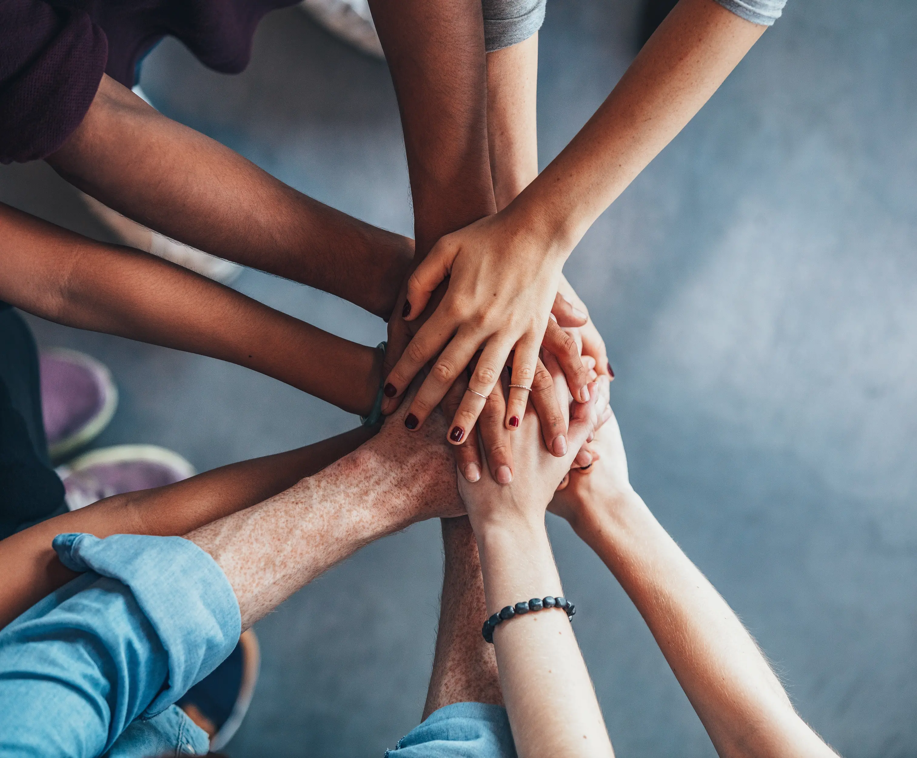 A diverse group of people with hands together, symbolizing unity and teamwork for overall wellbeing.