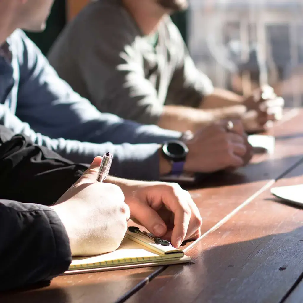 office employees resting forearms on wood meeting table