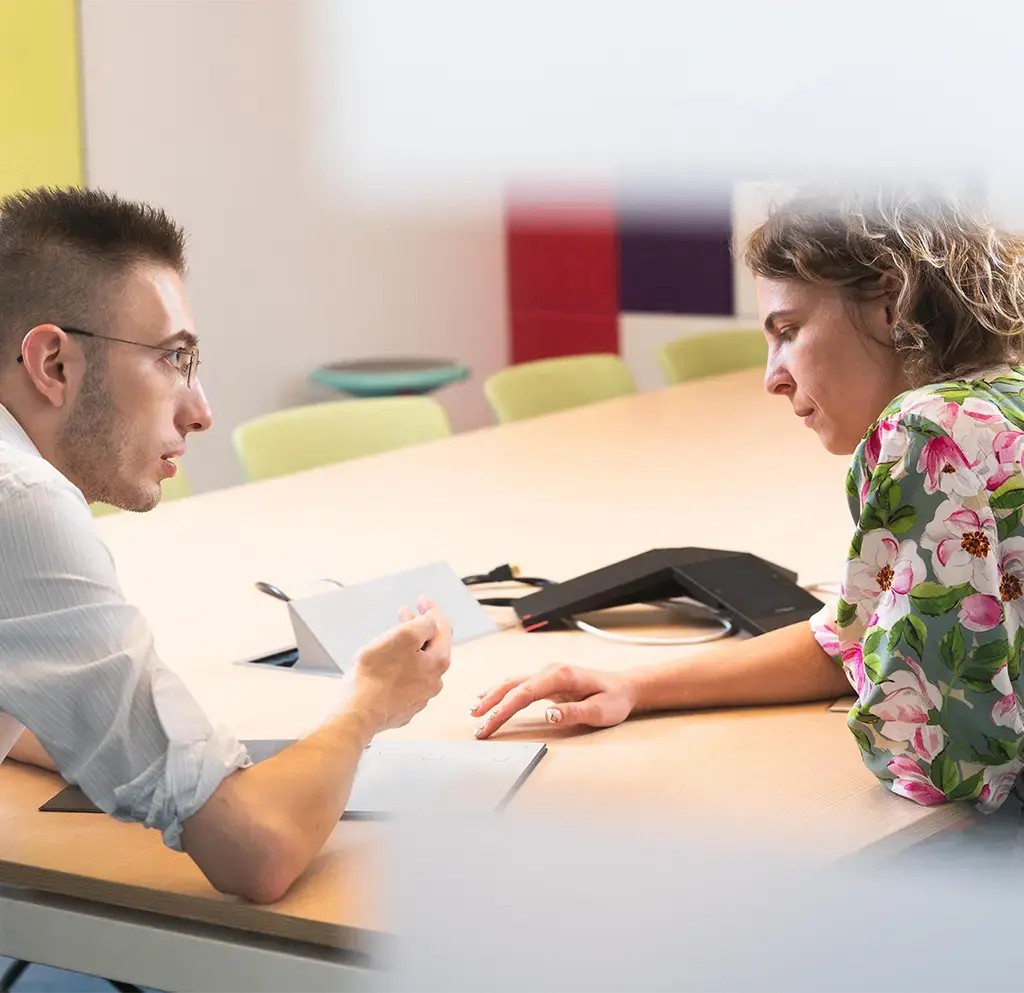 A man and a woman sitting at a conference table talking.