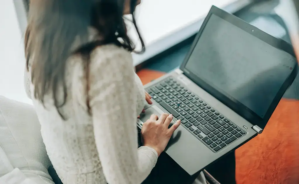 view of woman working on her laptop by orange run from outside glass divider